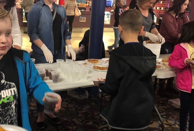 Team members handing out pizza at community Involvement movie theater event