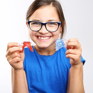 Little girl holding two retainers