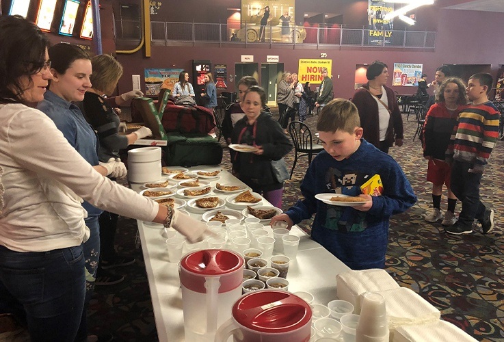 Teens handing out beverages at community Involvement movie theater event