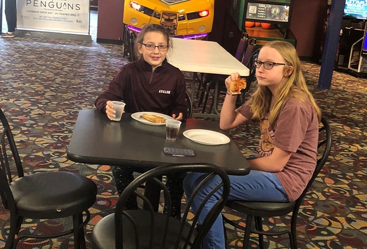 Two teens enjoying pizza at community Involvement movie theater event