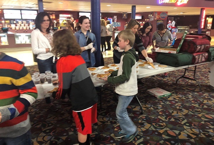 Smiling team members handing out food at community Involvement movie theater event