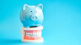 Piggy bank on model teeth representing cost of clear aligners in Bethel Park 