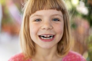 Girl in pink shirt smiling with braces