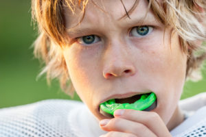 Young male who is taking out mouthguard after physical activity