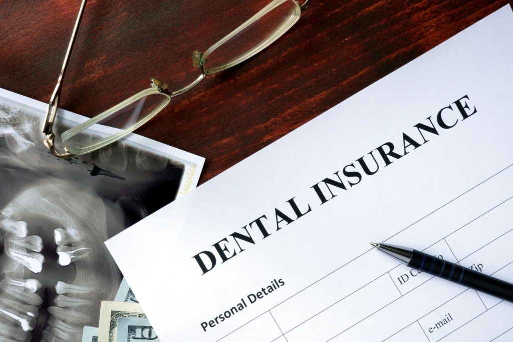 Dental insurance paperwork lying next to glasses and X-ray