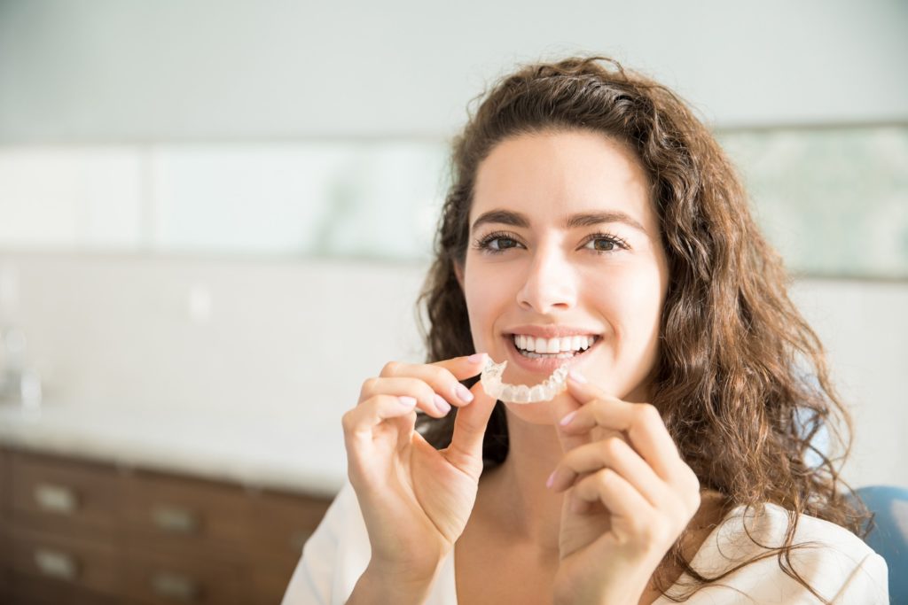 Woman smiling while putting in clear braces