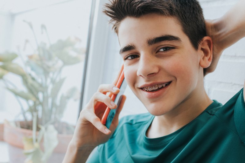 A young boy with braces on his cell phone