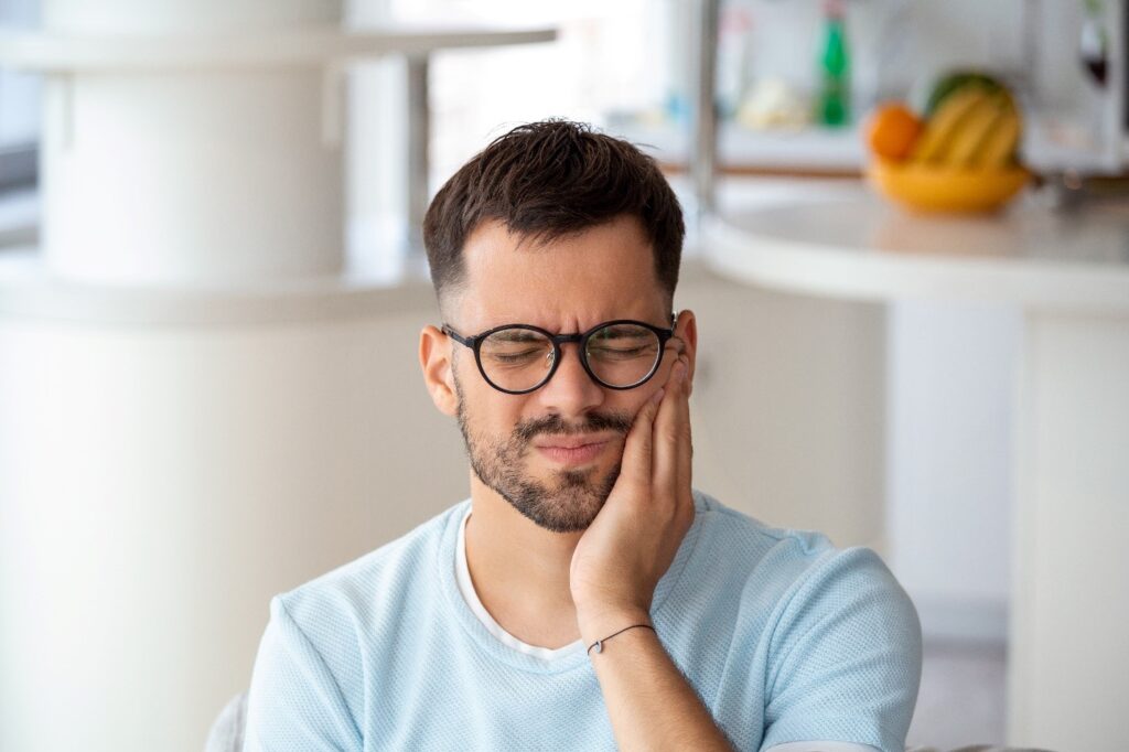 Closeup of man experiencing clear aligner discomfort at home